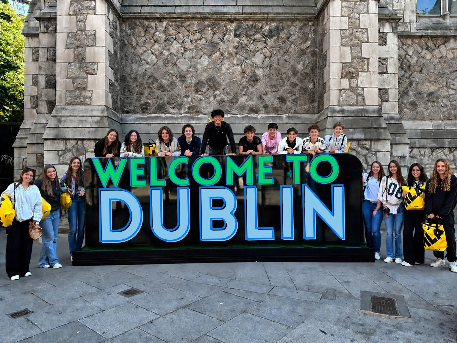 A group of teenagers in front of the Welcome to Dublin sign