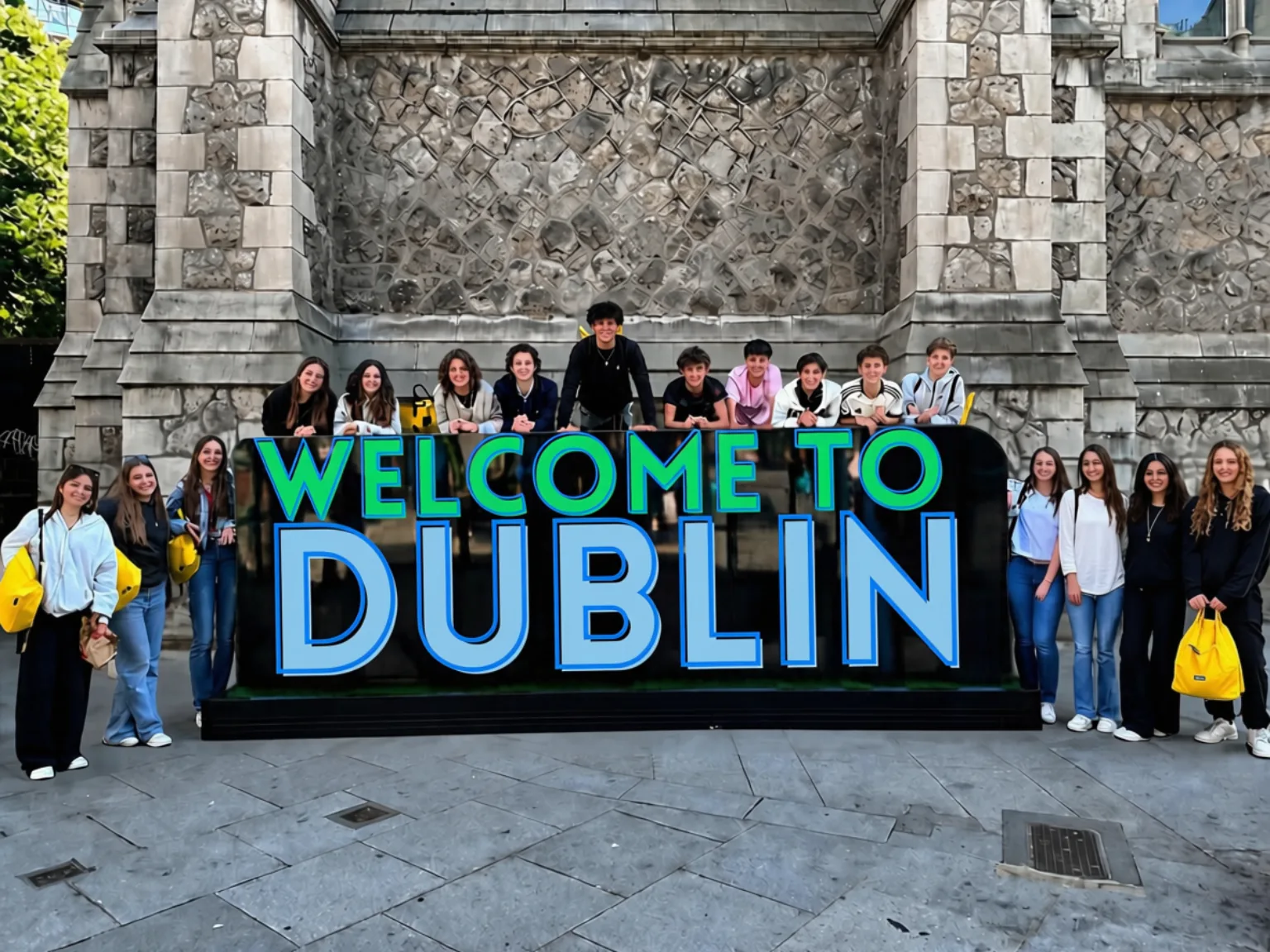 A group of teenagers in front of the Welcome to Dublin sign